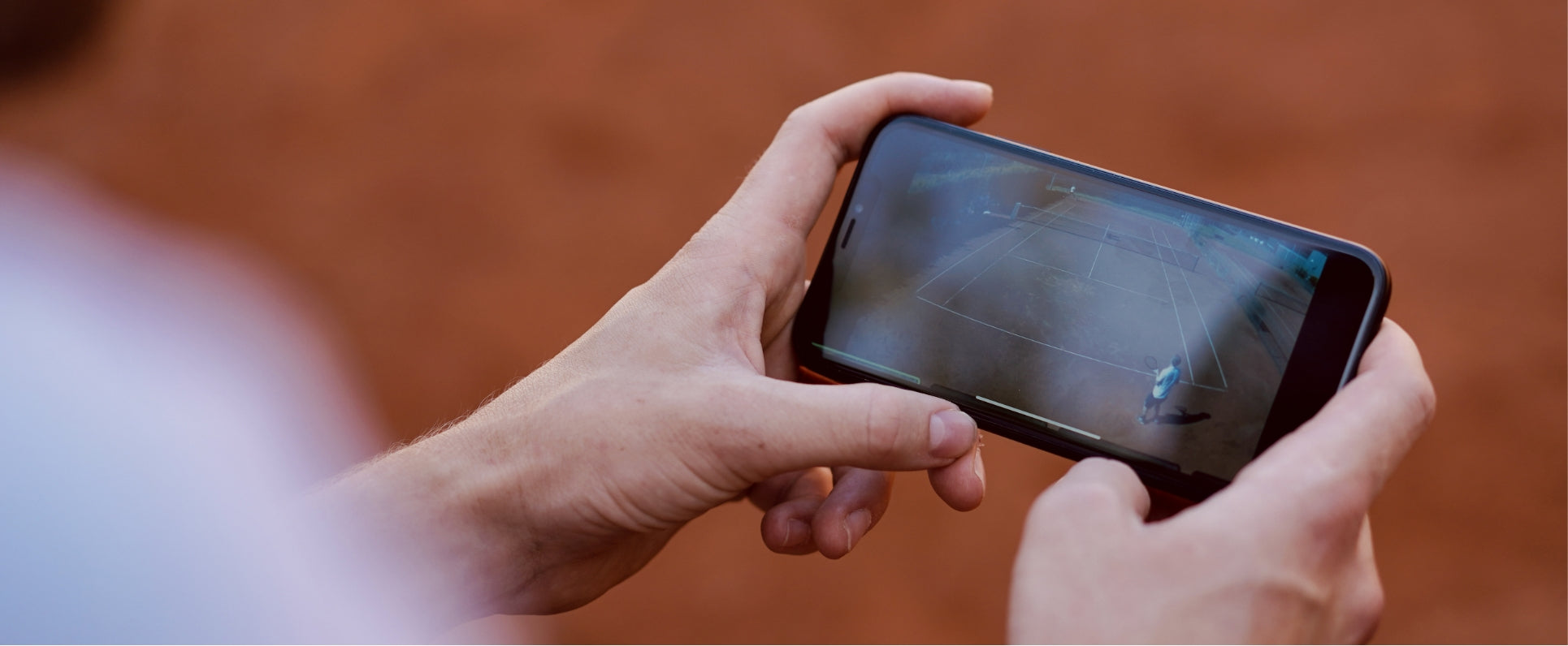 Man holding smartphone with video of tennis match playing.